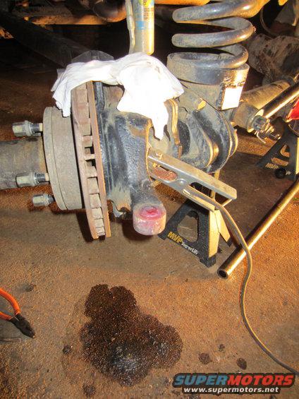 vehicle's front suspension assembly on jack stands, with brake rotor and coil spring visible