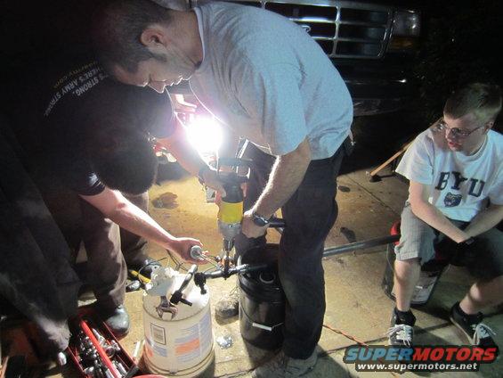 Front grille of a 1990s Ford truck, with people working on something below it