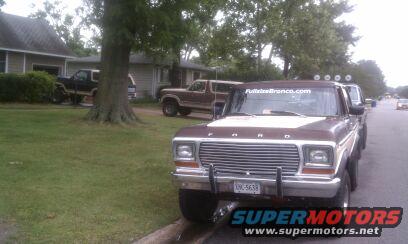brown Ford F-Series truck parked on street, another brown SUV and black truck in driveway