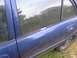 1999 Ford Escort - The side of a blue sedan is visible, with a reflection of a house and an American flag in the window.
