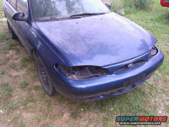 Blue 1999 Ford Escort sedan, front view, missing headlights