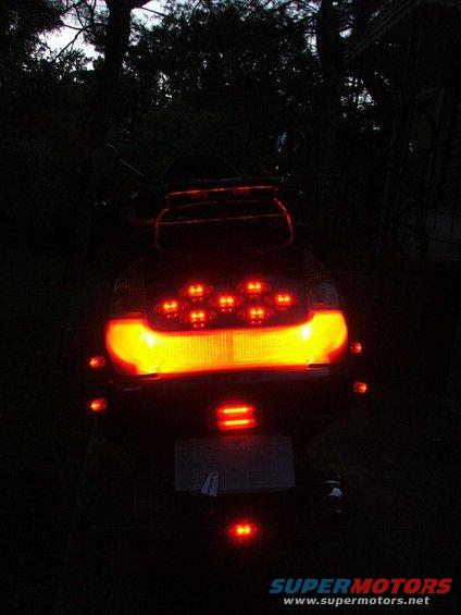 Rear view of a scooter with illuminated tail lights and brake lights