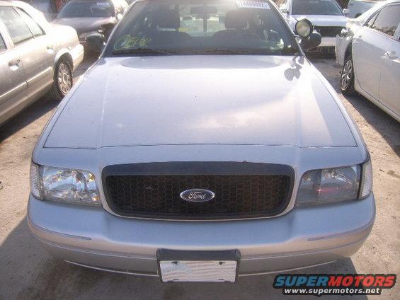 2005 Ford Crown Victoria front view, showing grille and headlights. Other vehicles are parked nearby