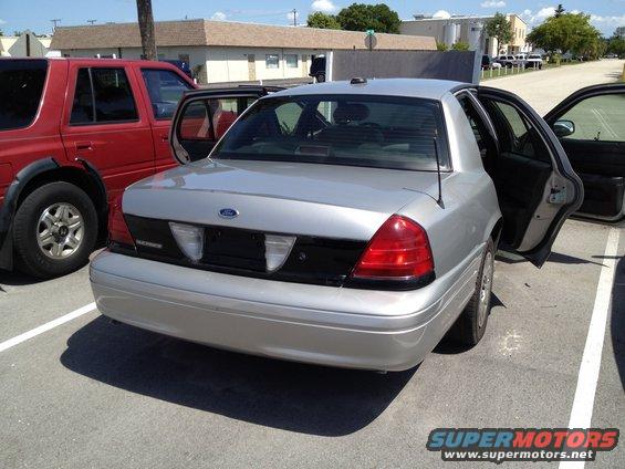 Silver 2005 Ford Crown Victoria parked next to a red SUV, rear view with doors open