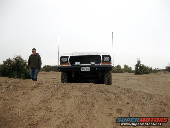 Front view of a white Ford truck with a man walking by some bushes