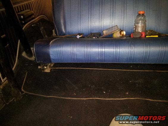 Back seat and floor of a vehicle with a bottle of water and some tools on the seat