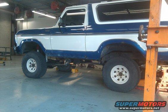 Blue and white Ford Bronco on lifts in a garage