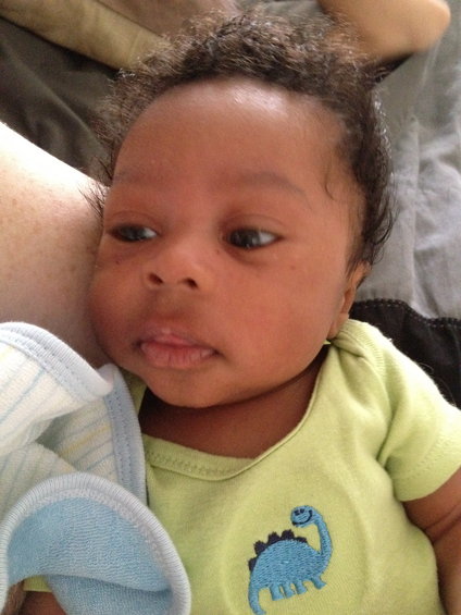 Close-up of a baby's face with a dinosaur on its shirt