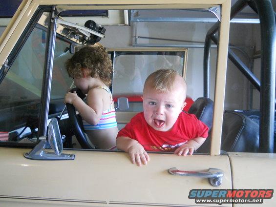 Kid in driver's seat, another kid in passenger seat, both looking out