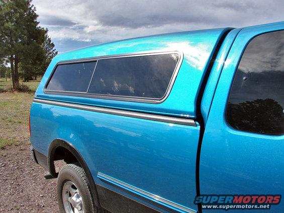 Blue 1998 Ford F-150 pickup truck side view with a camper shell