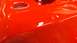 1983 Ford Bronco - A close-up view of a bright red painted metal component, showing its glossy finish and some minor imperfections.