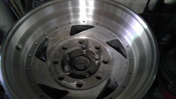 Close-up of an aftermarket aluminum wheel with a multi-lug pattern and triangular cutouts