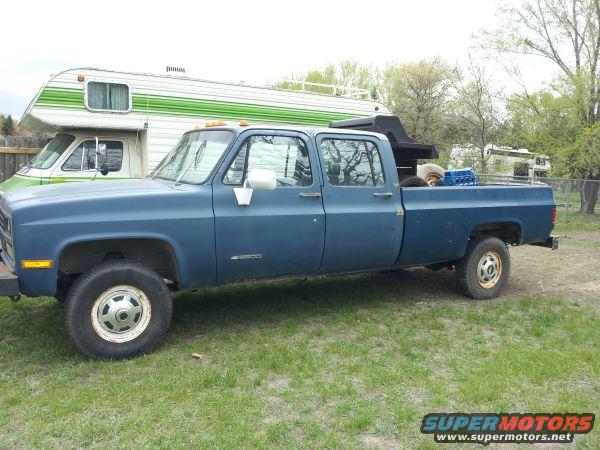 Blue crew cab pickup truck parked next to an RV