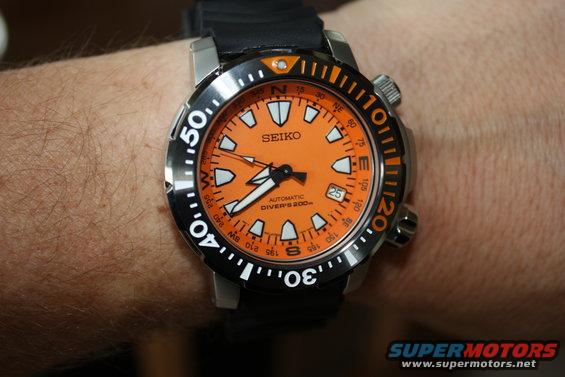 Orange dial Seiko automatic diver's watch with black strap on a person's wrist