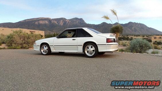 white Ford Mustang GT parked on asphalt with mountains and desert landscape in background