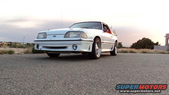 White 1989 Ford Mustang parked on asphalt with a cloudy sky