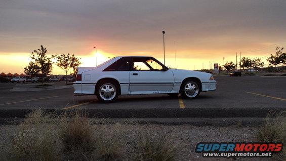 White 1989 Ford Mustang GT coupe parked in a lot at sunset, side view