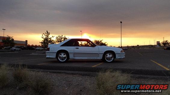 White 1989 Ford Mustang GT parked in a parking lot at sunset