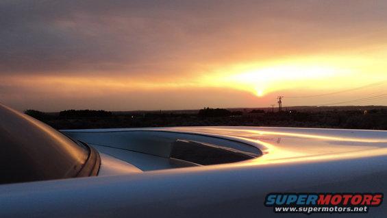 White car hood and windshield against a sunset sky