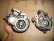 1989 Ford Probe - Two turbochargers are shown side-by-side on a cardboard surface. One is being held by a person's hand.