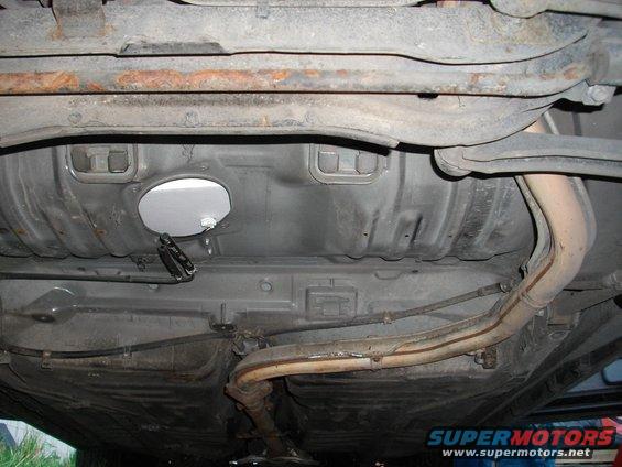 Underside view of a car showing the fuel tank, exhaust pipes, and suspension components