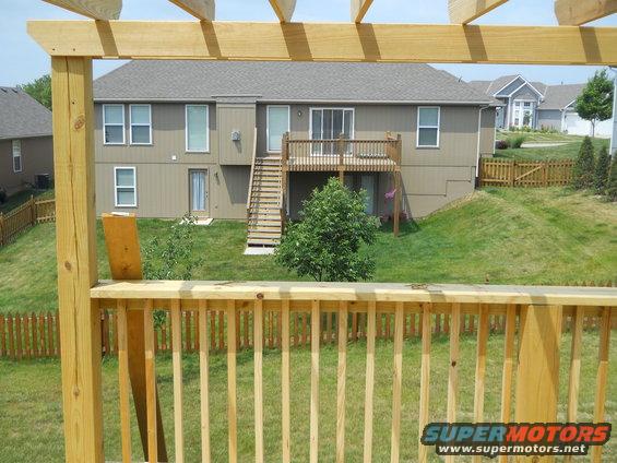 Backyard scene with wooden deck and house, Supermotors logo visible