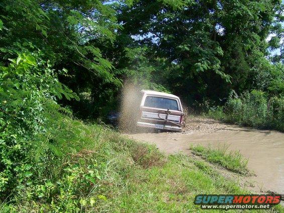 Ford Bronco kicking up water while driving on a muddy path