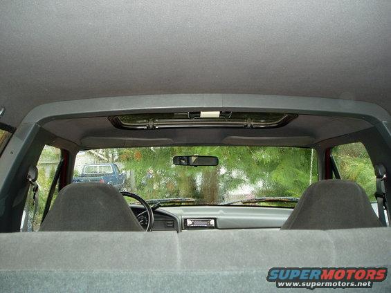 Interior view from back seat looking forward through windshield at another truck parked outside