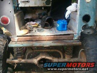 Rear cargo area of a vintage SUV, showing tools and parts. Watermark "SUPERMOTORS" visible