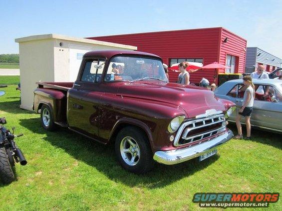 Maroon 1955 Chevrolet pickup truck parked on grass next to a silver car