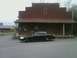 2004 Ford Crown Victoria - A black 2004 Ford Crown Victoria is parked in front of a rustic building.