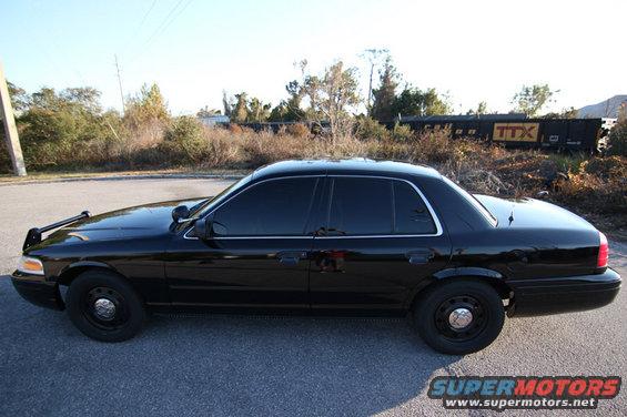 Black 2004 Ford Crown Victoria sedan with tinted windows and a push bar, viewed from the side