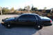 2004 Ford Crown Victoria - A black 2004 Ford Crown Victoria sedan is parked on the side of the road with a train car visible in the background.