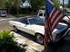 1973 Ford Ranchero - A white Ford Ranchero with a black top and hood is parked in a driveway, partially obscured by an American flag.