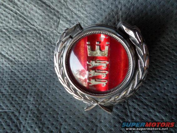 Emblem with red background and silver lions, possibly a hood ornament