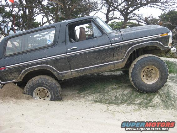 Black 1979 Ford Bronco stuck in sand, side view