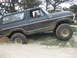 1979 Ford Bronco - This black 1979 Ford Bronco is stuck in the sand, with its front right tire partially buried.