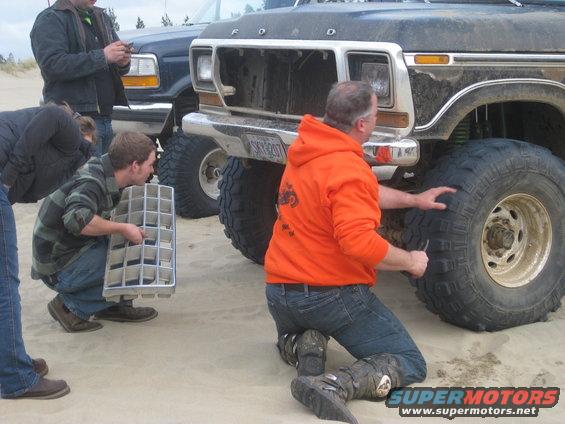 Ford truck with people checking the tires and grille. Another truck is behind it