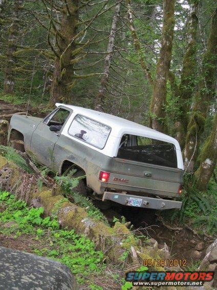 Two-tone GMC K5 Blazer navigating a steep, wooded trail