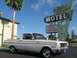 1965 Ford Ranchero - A white 1965 Ford Ranchero is parked in front of a vintage motel sign on a sunny day.