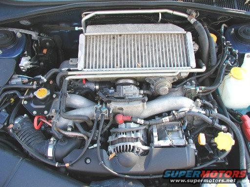Engine bay with intercooler, alternator, and various hoses and wires. Water reservoir visible