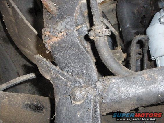 Close-up of a rusted vehicle frame with hoses attached