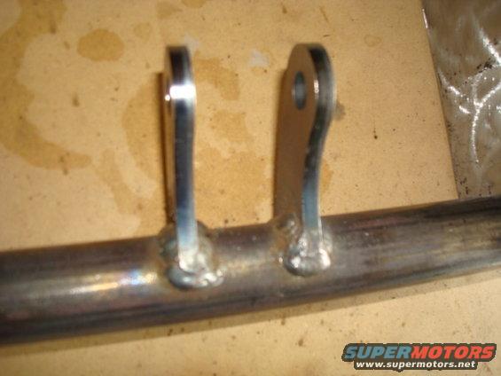 Two metal brackets welded onto a pipe, with visible weld marks