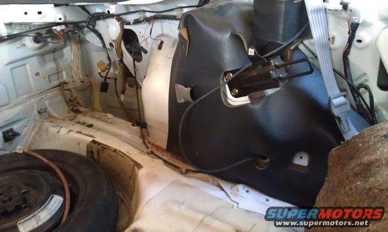 Car trunk interior showing spare tire and wiring harness. Supermotors.net logo visible