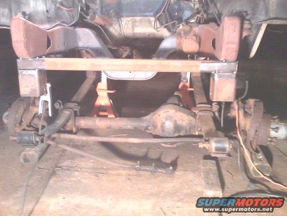 vehicle frame with front axle and suspension components, supported by jack stands