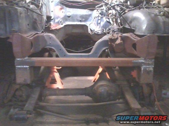 vehicle frame on jack stands with suspension components visible