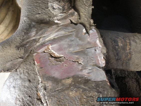 Close-up of heavily damaged and repaired metal frame section with visible cracks and rust