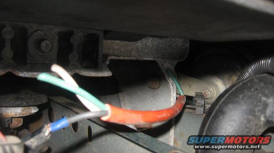 Wires with red and blue connectors near a metal bracket and black hose