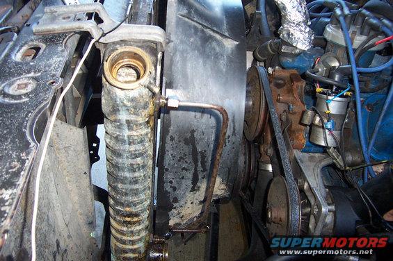 Close-up of a vehicle's engine bay, showing the radiator, fan, belts, and engine components