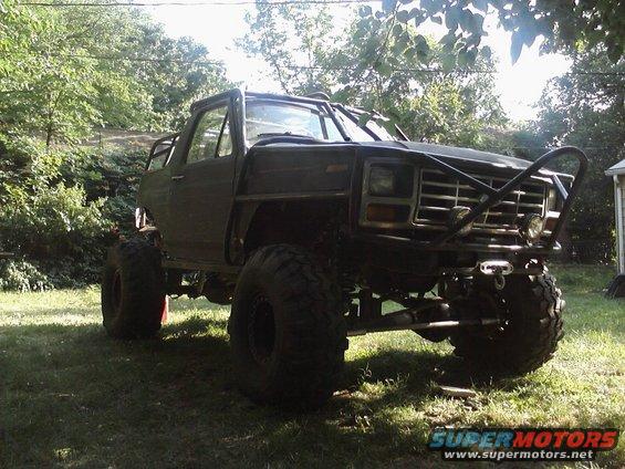Modified Ford Bronco with roll cage and large tires, parked on grass
